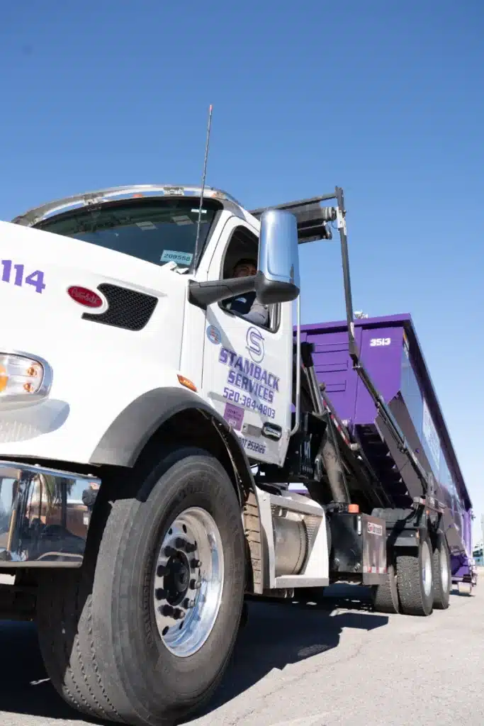 Stamback Services truck hauling a dumpster
