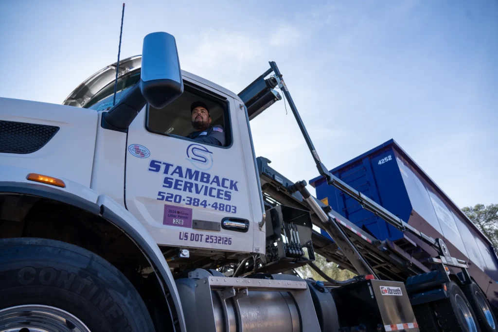 Stamback Services truck hauling a dumpster