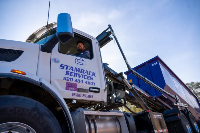 Stamback Services truck hauling a dumpster